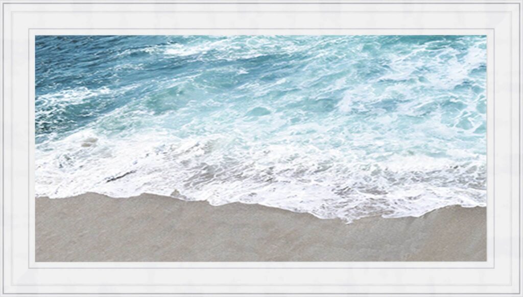 Framed photograph of turquoise ocean waves washing onto a sandy beach.